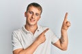 Young caucasian man wearing casual white polo smiling and looking at the camera pointing with two hands and fingers to the side Royalty Free Stock Photo