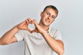 Young caucasian man wearing casual white polo smiling in love doing heart symbol shape with hands Royalty Free Stock Photo