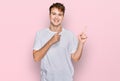 Young caucasian man wearing casual white t shirt smiling and looking at the camera pointing with two hands and fingers to the side Royalty Free Stock Photo