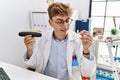 Young caucasian man wearing dentist uniform holding aligner and whitening test at clinic