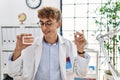 Young caucasian man wearing dentist uniform holding brackets and invisible aligner at clinic