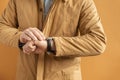 Young caucasian man wearing ginger colored coat and checking time on a wrist watch. Business man waiting for meeting. Royalty Free Stock Photo