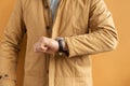 man wearing ginger colored coat and checking time on a wrist watch. Business man waiting for meeting. It's time Royalty Free Stock Photo