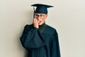 Young caucasian man wearing graduation cap and ceremony robe looking stressed and nervous with hands on mouth biting nails Royalty Free Stock Photo