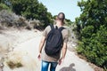 Man carrying a backpack walking by a dirt road