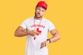 Young caucasian man wearing lifeguard t shirt holding whistle in hurry pointing to watch time, impatience, upset and angry for