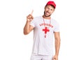 Young caucasian man wearing lifeguard t shirt holding whistle pointing finger up with successful idea