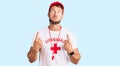 Young caucasian man wearing lifeguard t shirt holding whistle pointing up looking sad and upset, indicating direction with