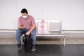 Young caucasian man wearing mask checking his smartphone while is waiting for the train to come Royalty Free Stock Photo