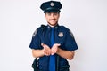 Young caucasian man wearing police uniform smiling with hands palms together receiving or giving gesture