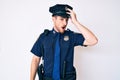 Young caucasian man wearing police uniform surprised with hand on head for mistake, remember error Royalty Free Stock Photo