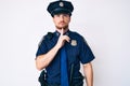 Young caucasian man wearing police uniform thinking concentrated about doubt with finger on chin and looking up wondering