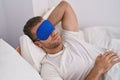 Young caucasian man wearing sleepmask lying on bed sleeping at bedroom