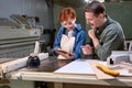 Young caucasian man and woman joiners using digital tablet while working in workshop Royalty Free Stock Photo