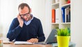 A young caucasian man working on a desk with a laptop and mobile phone. Royalty Free Stock Photo