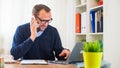 A young caucasian man working on a desk with a laptop and mobile phone. Royalty Free Stock Photo