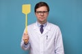 Young caucasian medical man doctor holding a fly swatter looking for insect or virus Royalty Free Stock Photo