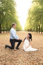 Man kneeling in front of his girlfriend and making marriage proposal in park Royalty Free Stock Photo