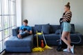 Young Caucasian man is lazy to do housework and playing online game with smartphone and tablet on Sofa. Wife holds a vacuum