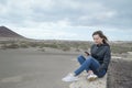 Young Caucasian millennial woman sitting on a stone bench by the surfing beach known as Playa El Medano, Tenerife, Canary Islands Royalty Free Stock Photo