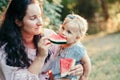 Young Caucasian mother with baby girl eating watermelon. Healthy finger food for babies. Summer sweet fruit food snack.