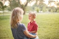 Young Caucasian mother and boy toddler son sitting together face to face. Family mom and child talking communicating outdoor on a Royalty Free Stock Photo