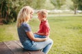 Young Caucasian mother and boy toddler son sitting together face to face. Family mom and child talking communicating outdoor on a Royalty Free Stock Photo