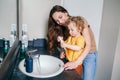 Young Caucasian mother helping boy toddler brush teeth in bathroom at home. Health hygiene and morning routine for children. Mom Royalty Free Stock Photo