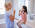 Young caucasian mother and her little daughter brushing their teeth with toothbrushes in the morning.Teaching your Royalty Free Stock Photo