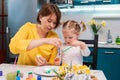 Young caucasian mother and her toddler daughter painting eggs. Concept of Easter celebration and traditions Royalty Free Stock Photo