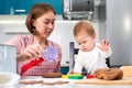 A young caucasian mother makes cookies with her baby. Close-up portrait. Kitchen in the background. The concept of home-made food Royalty Free Stock Photo