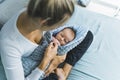 Young caucasian mother sitting cross-legged on bed and holding her infant baby boy. Adorable kid. Motherhood concept Royalty Free Stock Photo