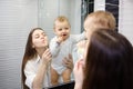 Young caucasian mother teaching baby boy how to brush teeth with toothbrush