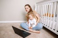 Young Caucasian mother with toddler baby boy watching cartoons on laptop at home together. Family mom with kid using technology. Royalty Free Stock Photo