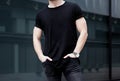 Young caucasian muscular man wearing black tshirt and jeans posing in center of modern city. Blurred background Royalty Free Stock Photo