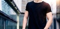 Young caucasian muscular man wearing black tshirt and jeans posing on the street of the modern city. Blurred background Royalty Free Stock Photo
