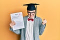 Young caucasian nerd man wearing glasses and graduation cap holding passed exam screaming proud, celebrating victory and success Royalty Free Stock Photo