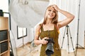Young caucasian photographer girl holding professional camera at photography studio stressed and frustrated with hand on head,