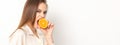 Young caucasian pretty cunning brunette woman biting one orange half and looking at the camera wearing a white shirt Royalty Free Stock Photo