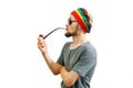 Young caucasian rasta man in jamaica hat, sunglasses and grey t-shirt on white background with smoke pipe in hand Royalty Free Stock Photo