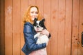 Young caucasian red-haired woman holding a dog of Chihuahua breed on her hands on a wooden background. The theme of love for Royalty Free Stock Photo