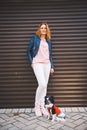 A young Caucasian red-haired woman stands near a city embossed wall with her pet dog, a Chihuahua breed. Walk with a funny dog in Royalty Free Stock Photo