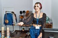 Young caucasian shopkeeper woman smiling happy giving dollars at clothing store