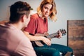 Young caucasian short-haired blond woman playing ukulele for man Royalty Free Stock Photo