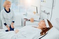 Young caucasian sick woman in hospital and her sympathetic nurse