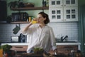 Young caucasian smiling woman drinking orange juice while standing in the kitchen at home Royalty Free Stock Photo