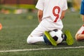Young caucasian soccer player sitting on soccer at football pitch. Little boys on sports training watching training game Royalty Free Stock Photo