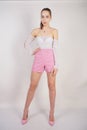 A young caucasian teen girl in a white transparent blouse and checkered pink short shorts showing summer fashion clothes and posin Royalty Free Stock Photo