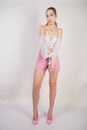 A young caucasian teen girl in a white transparent blouse and checkered pink short shorts showing summer fashion clothes and posin Royalty Free Stock Photo