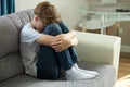 Young caucasian teenage boy sitting alone on sofa, face down crying Royalty Free Stock Photo